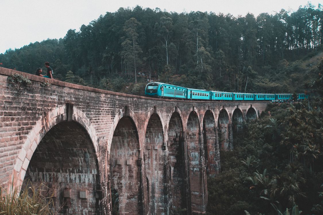 Train vs Private Driver in Sri Lanka: Which Is Best? 2 Blue train crossing the Nine Arch Bridge in Ella, Sri Lanka, surrounded by green forest